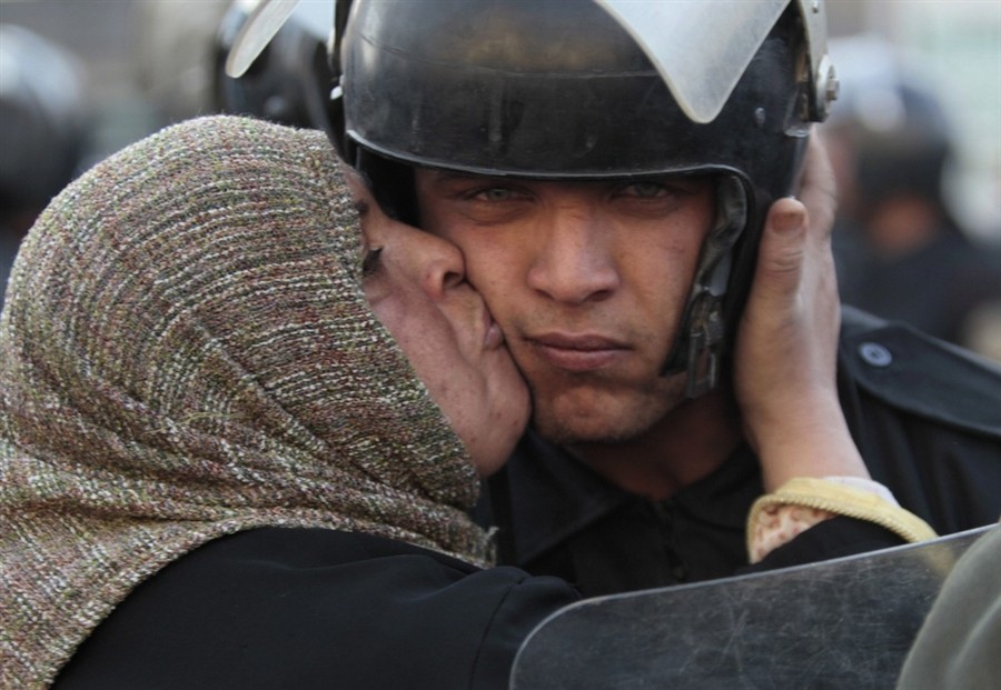 1. Cairo, Egypt (2011) - A woman kisses an anti-protest policeman while protesting against Mubarak’s government.