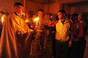 Capt. Sean Levine, chaplain, 117th Infantry Battalion, 2nd Stryker Brigade Combat Team, presents the trikeri or triple candle, which represents the Holy Trinity, for the observers to light candles during an Eastern Orthodox Easter or Pascha (a Christian version of Passover) service at Kandahar Airfield, Afghanistan, April 23.