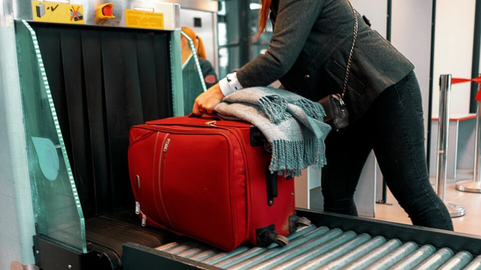 Red luggage going through airport screening device